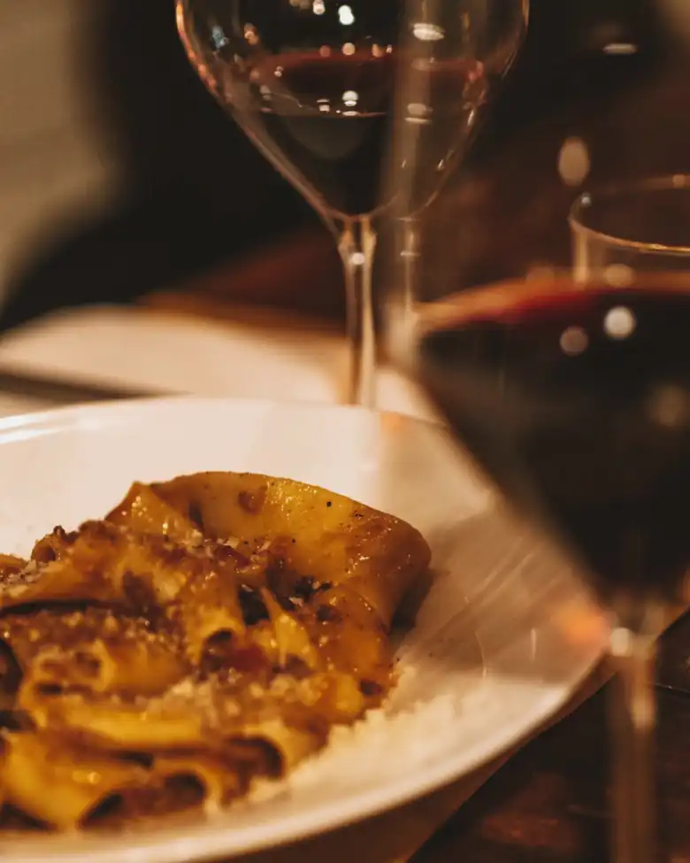 Un piatto di pasta e un bicchiere di rosso, sotto la lampada. Foto: @ilsevdhave.